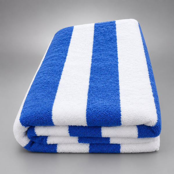 Cabana Stripe Pool Towel folded on a dark wooden table, white with royal blue stripes