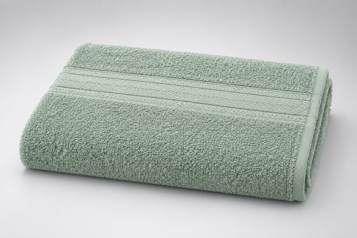Value Bath Towel in Sage Grey laid flat on a wooden surface